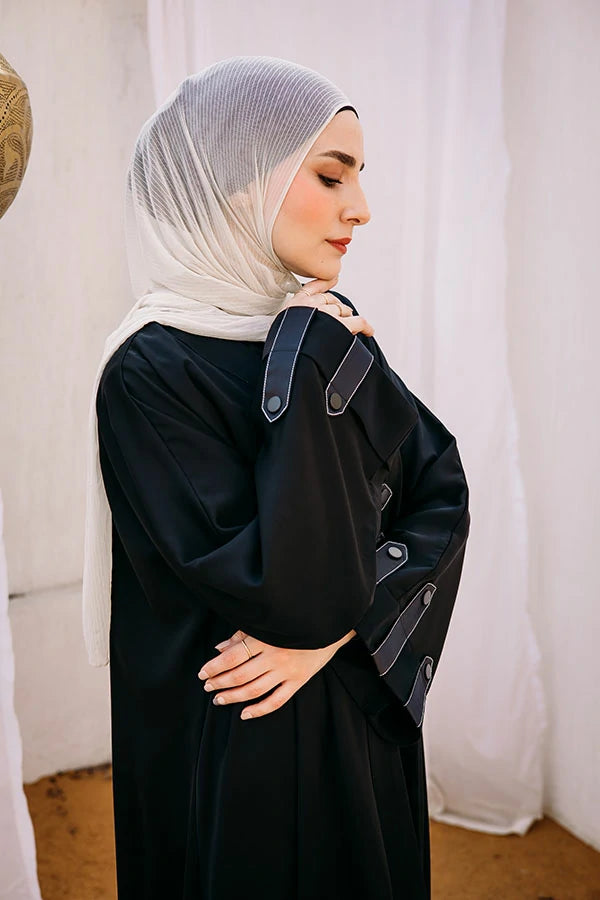 Cloche silk abaya with satin belts on sleeves and chest.